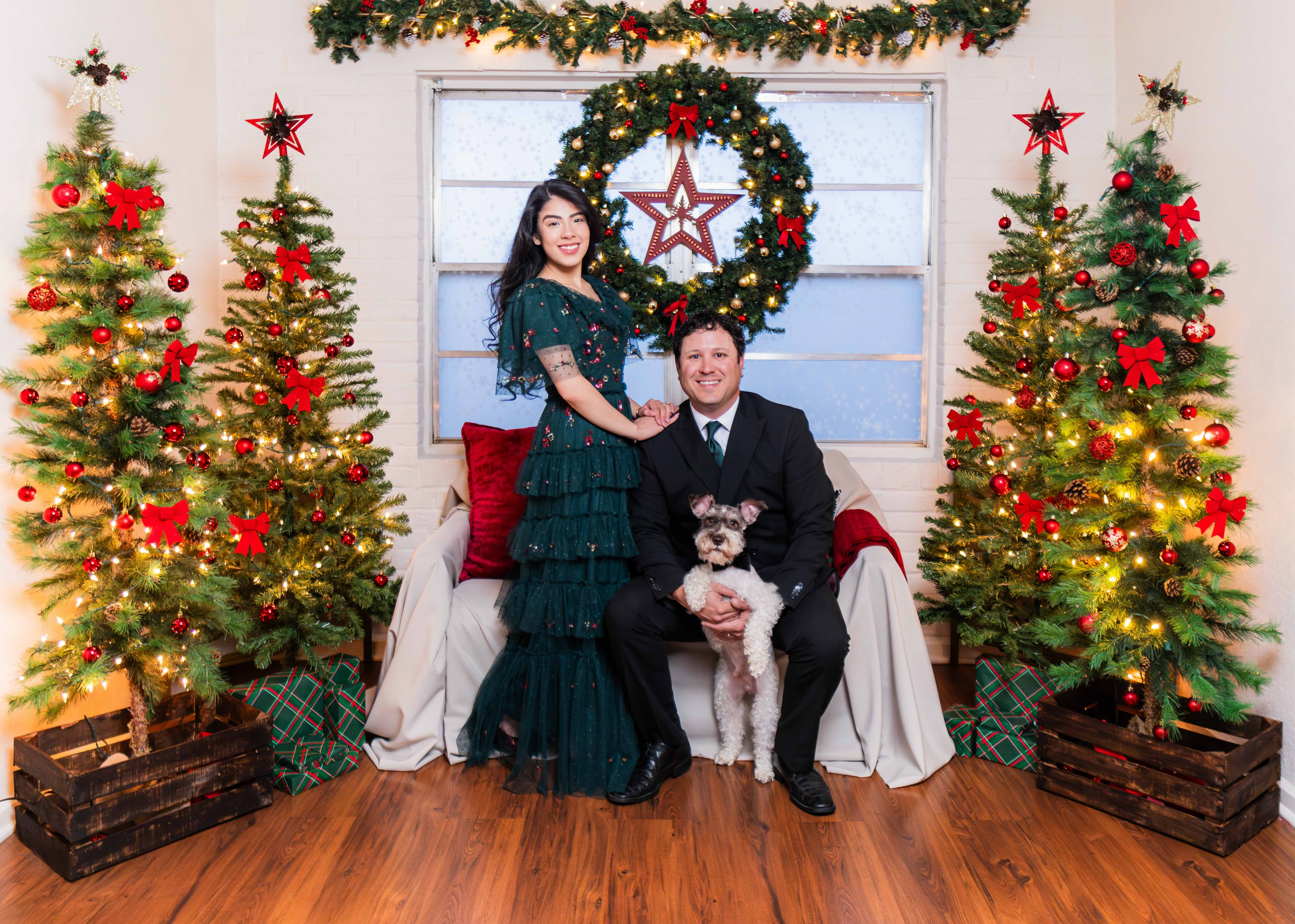 Couple poses with their pet with a Christmas backdrop by Bee Beautiful Studios in McAllen, Texas